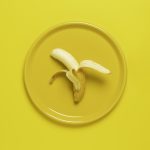Photo of peeled banana on yellow plate and background