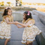 2 girls in white floral dress dancing on the street