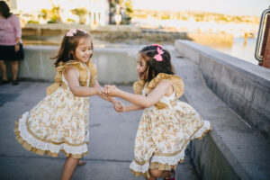 2 girls in white floral dress dancing on the street