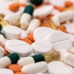Bunch of white oval medication tablets and white medication capsules