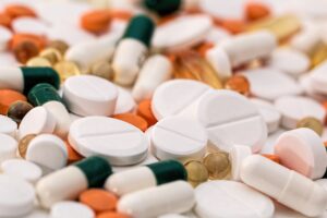 Bunch of white oval medication tablets and white medication capsules